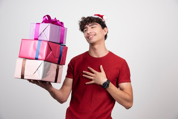 Hombre joven con cajas de regalo sintiéndose satisfecho