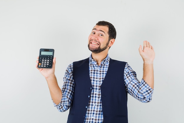 Hombre joven con calculadora, mostrando la palma en camisa