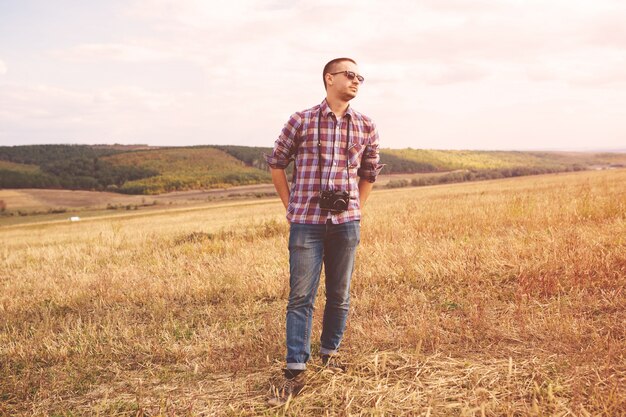 Hombre joven con cámara de fotos retro hipster al aire libre Estilo de vida