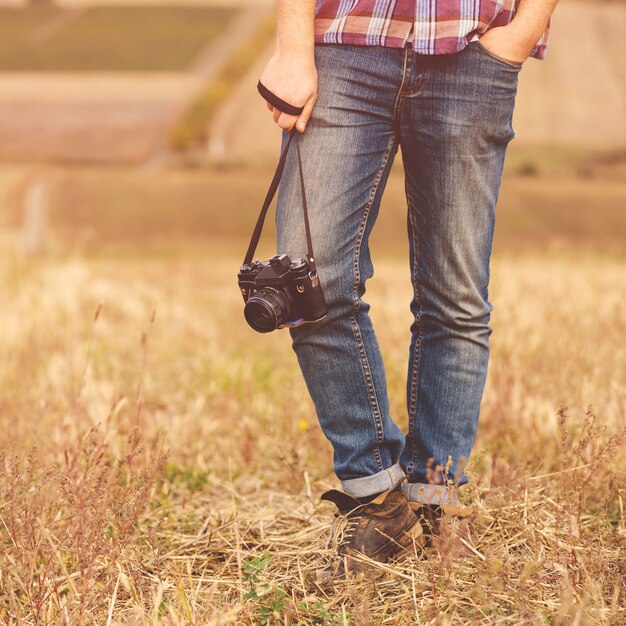 Hombre joven con cámara de fotos retro hipster al aire libre Estilo de vida