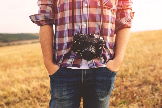 Hombre joven con cámara de fotos retro hipster al aire libre Estilo de vida