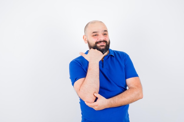 Hombre joven con camisa azul que muestra el gesto de llamada telefónica, vista frontal.