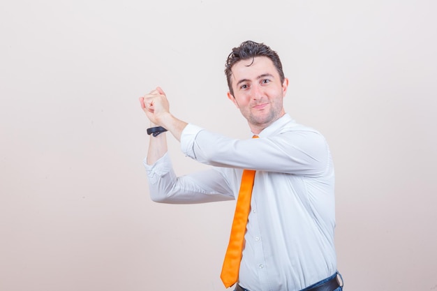 Foto gratuita hombre joven con camisa blanca, jeans gesticulando como si se preparara para soltar la flecha