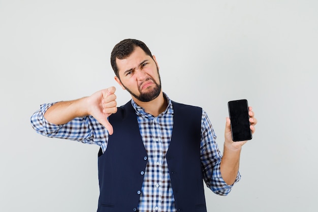 Foto gratuita hombre joven en camisa, chaleco sosteniendo teléfono móvil