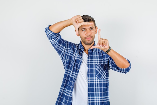 Hombre joven en camisa haciendo gesto de marco y mirando confiado, vista frontal.