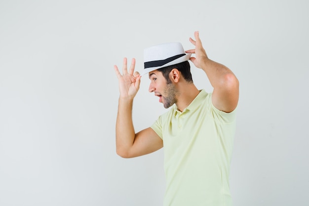 Hombre joven en camiseta ajustando su sombrero y luciendo elegante