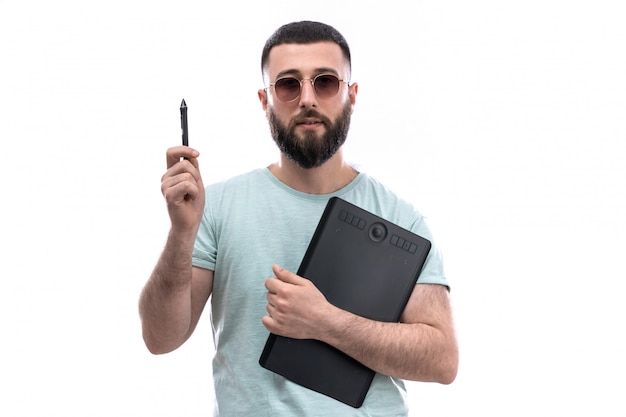 Hombre joven en camiseta azul con barba y gafas de sol con archivos de pluma