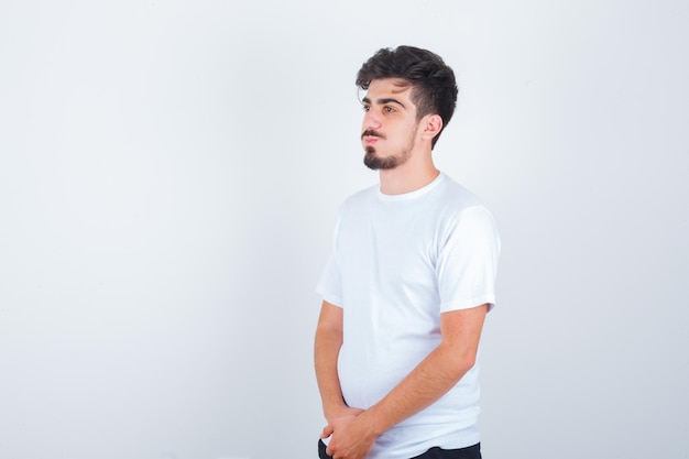 Hombre joven en camiseta blanca mirando a otro lado y mirando pensativo