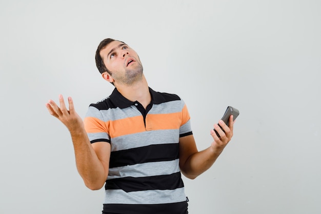 Hombre joven en camiseta mirando hacia arriba después de leer el mensaje y mirando preocupado