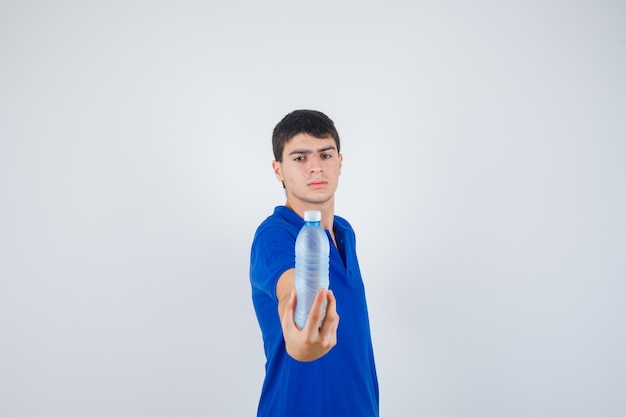 Hombre joven en camiseta mostrando una botella de plástico y mirando confiado, vista frontal.