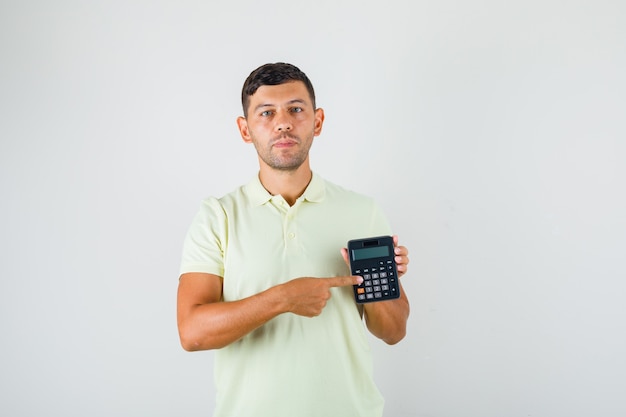 Hombre joven en camiseta mostrando calculadora en su mano