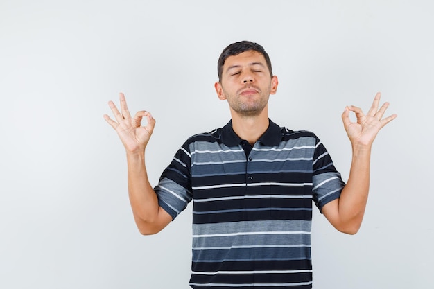 Foto gratuita hombre joven en camiseta mostrando gesto ok y mirando pacífica, vista frontal.