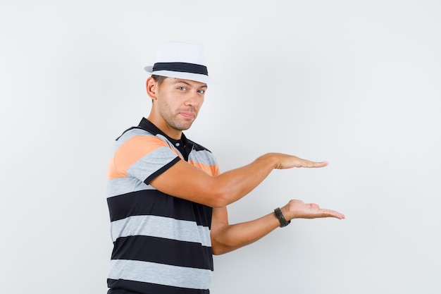 Hombre joven en camiseta y sombrero mostrando letrero de tamaño pequeño