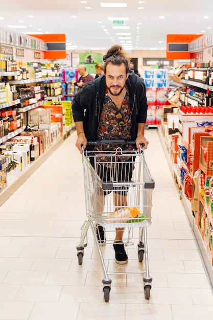 Hombre joven con carro de compras en supermercado