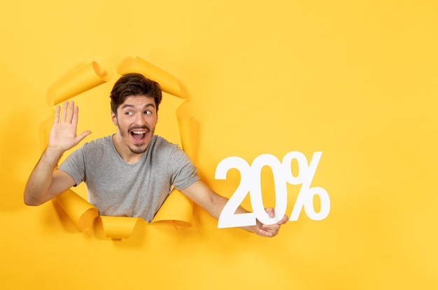 Foto gratuita hombre joven con cartel de inscripción en el chico de compras de venta de fondo de papel amarillo roto