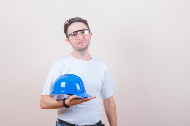 Foto gratuita hombre joven con casco en camiseta, jeans y mirando alegre