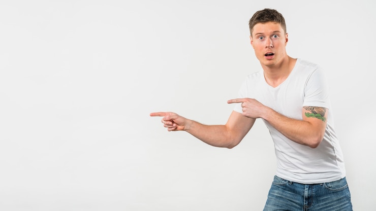 Foto gratuito hombre joven chocado que señala sus dedos en algo aislado en el fondo blanco