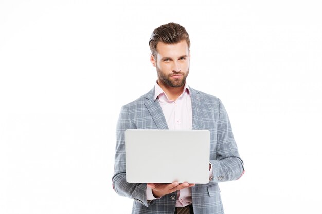 Hombre joven concentrado que usa la computadora portátil.