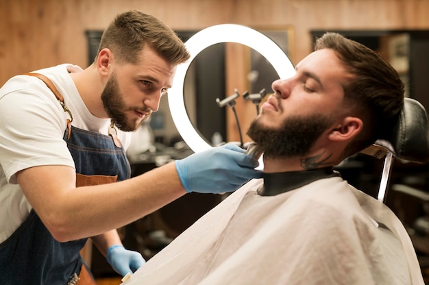 Hombre joven consiguiendo su barba con estilo en el peluquero