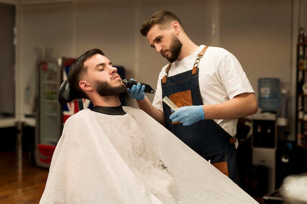 Hombre joven consiguiendo su barba con estilo en el peluquero