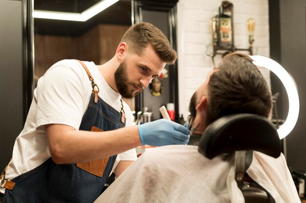 Hombre joven consiguiendo su barba con estilo en el peluquero