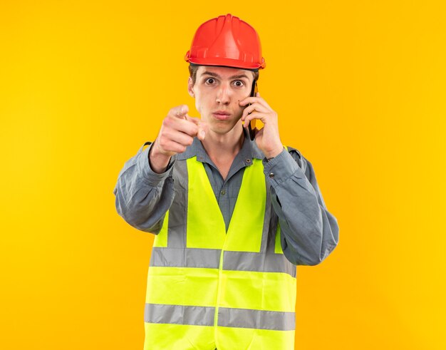Hombre joven constructor estricto en uniforme habla sobre puntos de teléfono en la cámara