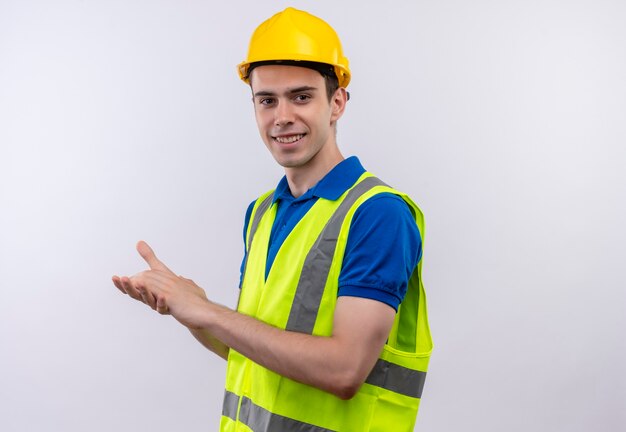 Hombre joven constructor vestido con uniforme de construcción y casco de seguridad feliz aplaude