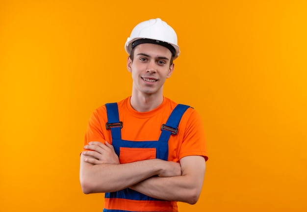 Hombre joven constructor vestido con uniforme de construcción y casco de seguridad sonríe