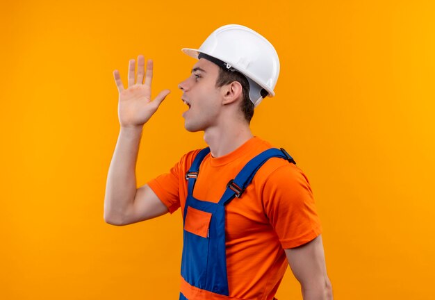 Hombre joven constructor vestido con uniforme de construcción y llamadas de casco de seguridad