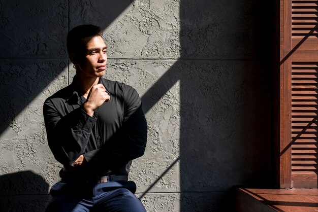 Hombre joven contemplado sentado frente a la pared