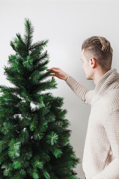 Hombre joven decorando árbol de navidad