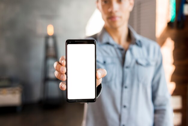 Hombre joven Defocused que muestra el teléfono móvil de la pantalla blanca