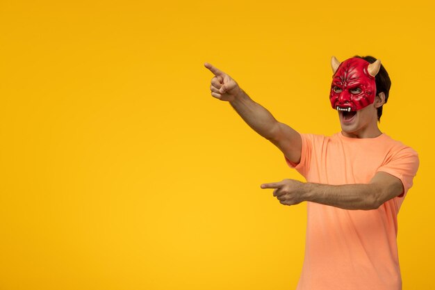 Hombre joven con dibujos animados de fondo amarillo de máscara de diablo aterrador