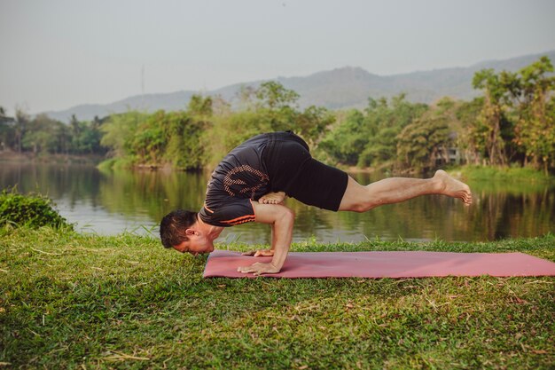 Hombre joven en difícil postura de yoga