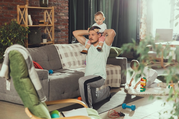 Hombre joven ejercicio de fitness, aeróbicos, yoga en casa, estilo de vida deportivo.