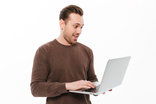 Hombre joven emocionado que usa la computadora portátil.