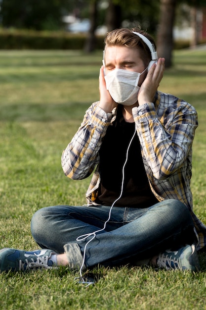 Hombre joven con estilo con mascarilla escuchando música