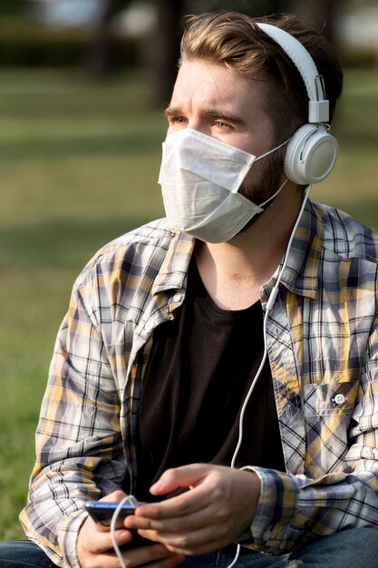 Hombre joven con estilo con mascarilla escuchando música