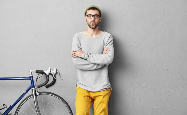 Hombre joven con estilo de pie junto a la bicicleta