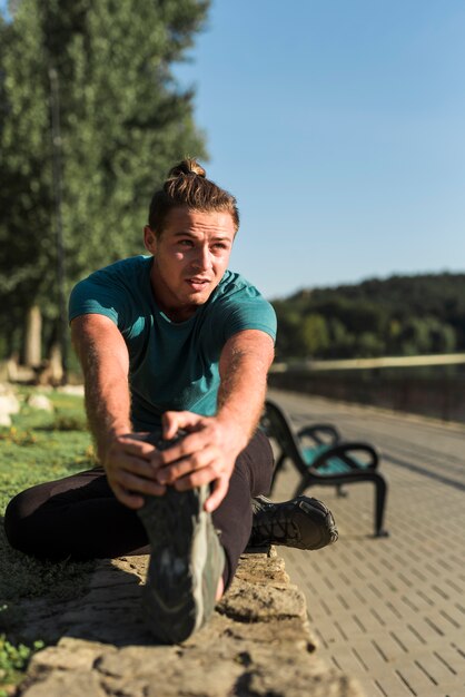 Hombre joven estirando en el parque