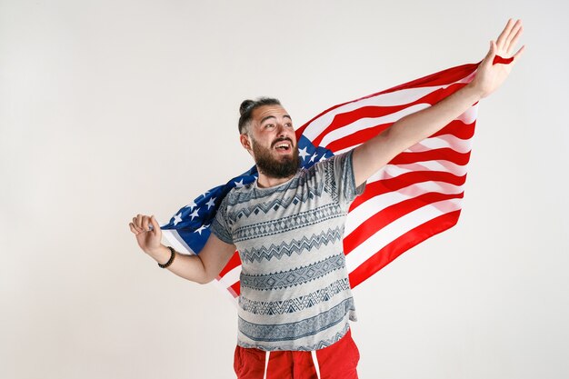 Hombre joven feliz con la bandera de los Estados Unidos de América aislado en el estudio blanco.