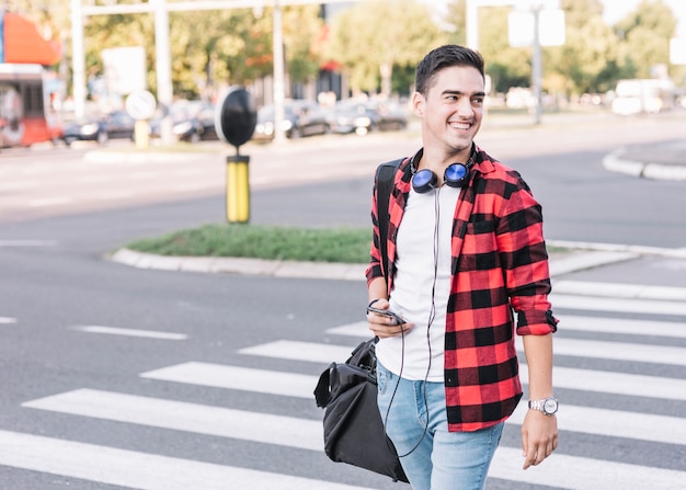 Hombre joven feliz con calle de cruce de teléfono celular