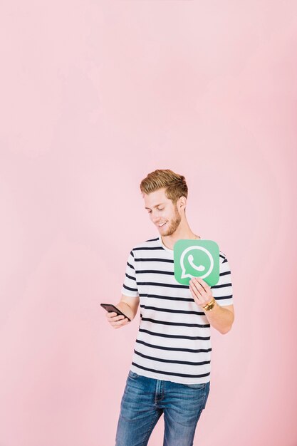 Hombre joven feliz con icono de WhatsApp con smartphone