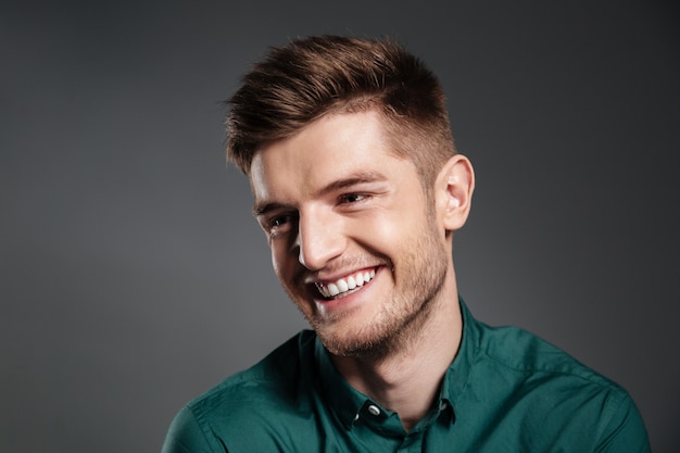 Hombre joven feliz que presenta aislado sobre gris