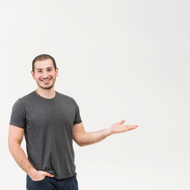 Hombre joven feliz que presenta sobre fondo blanco