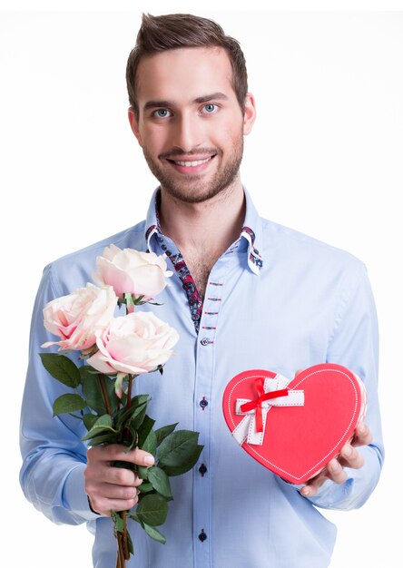 Hombre joven feliz con rosas rosadas y un regalo - aislado en blanco.