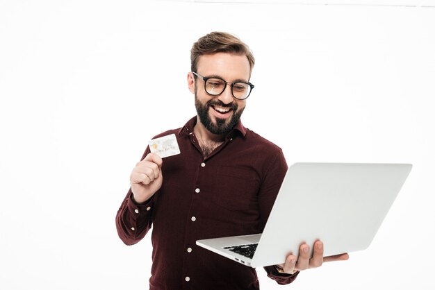 Hombre joven feliz con tarjeta de crédito y computadora portátil. comprar en linea