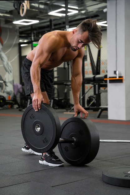 Hombre joven en forma trabajando con pesas en el gimnasio