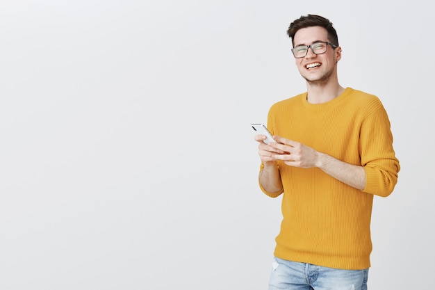 Hombre joven con gafas riendo como mediante teléfono móvil