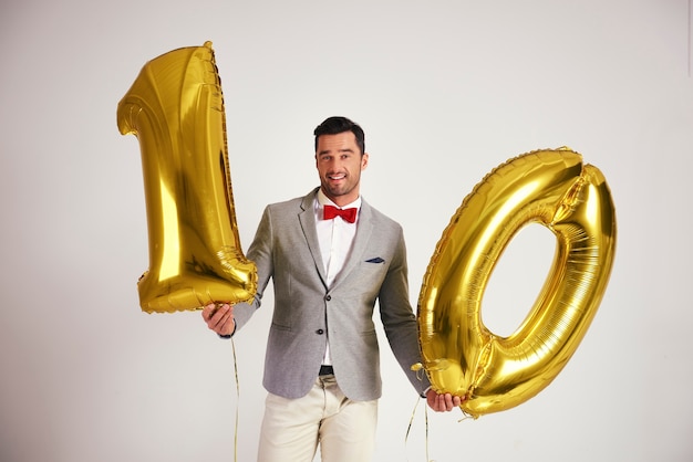 Foto gratuita hombre joven con globo dorado en forma 10